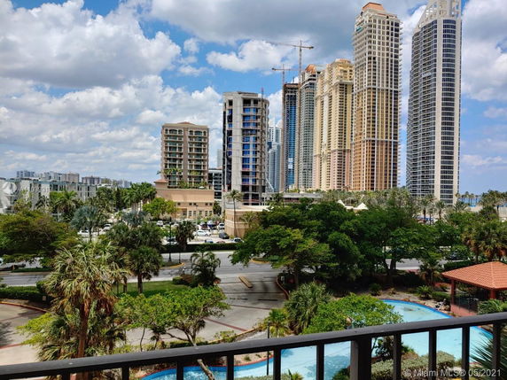 View of tall buildings from a distance with trees and a street in the foreground.