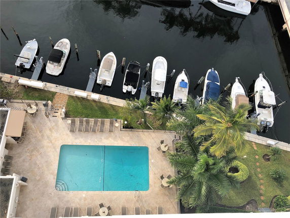View from a rooftop showing a swimming pool area and docked boats in a marina.