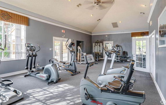 Room with exercise equipment, including stationary bicycles and elliptical machines.