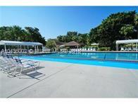Outdoor view of a swimming pool area with lounge chairs and surrounding trees.