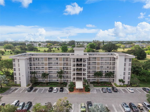 Front view of a multi-story apartment building with adjacent parking area.