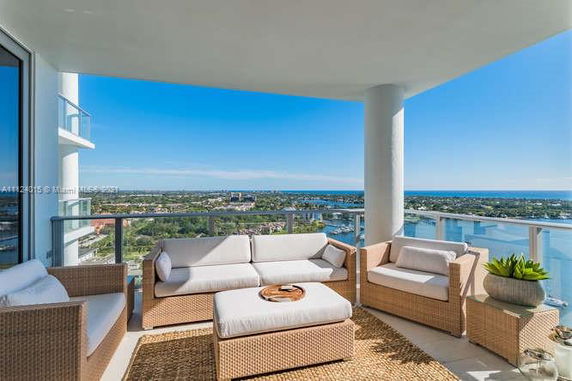 Panoramic view from a balcony with outdoor seating overlooking the city and water.