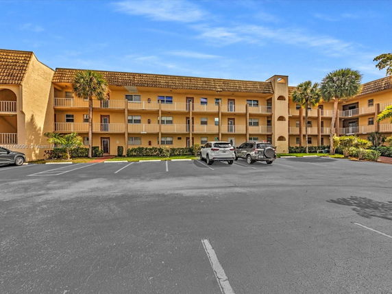 Front view of a multi-story building with a parking area in front.
