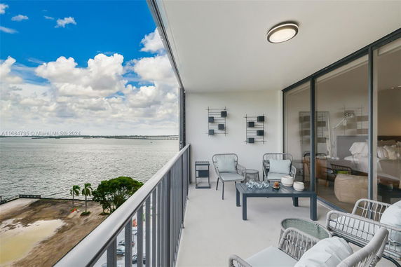 Balcony with seating area overlooking a large body of water.