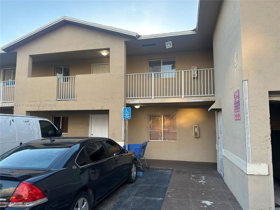 Front view of a two-story residential building with balconies and parking area.