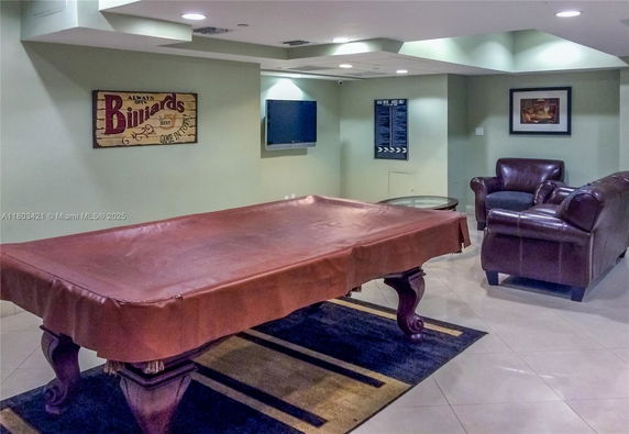 Recreational room with a covered billiards table and seating area.