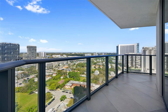 Panoramic view of cityscape from a balcony with glass railing.