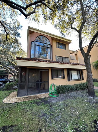 Front view of a two-story house with a large arched window and tiled roof.