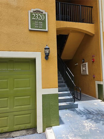 Front view of a building with a staircase and a green garage door.
