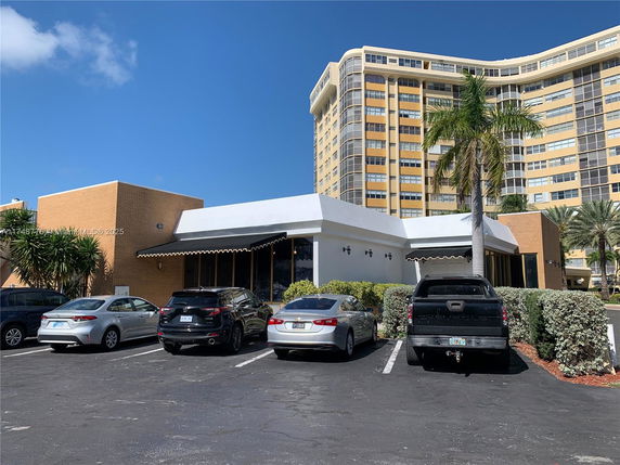 Outdoor parking area in front of a modern building with several parked cars.