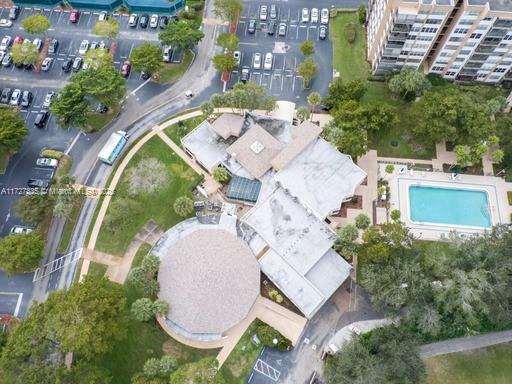 Aerial view of a building complex with a flat rooftop, swimming pool, and parking lot.