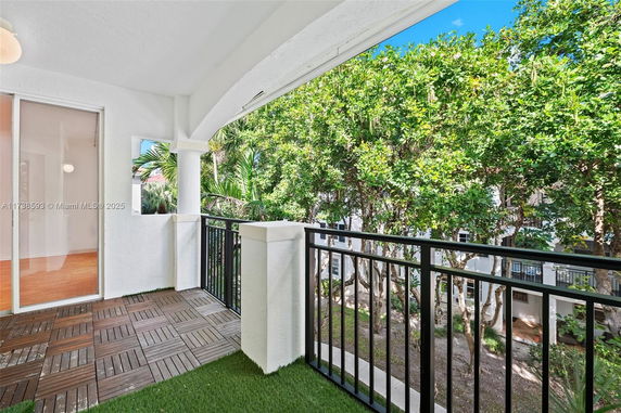 View from a balcony with railings and a wooden floor, overlooking trees.