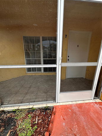 Front view of an apartment with a screened patio and tiled floor.