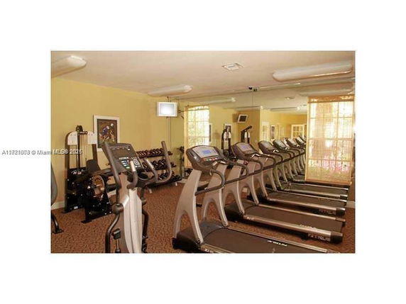 Indoor gym with rows of treadmills and exercise equipment.