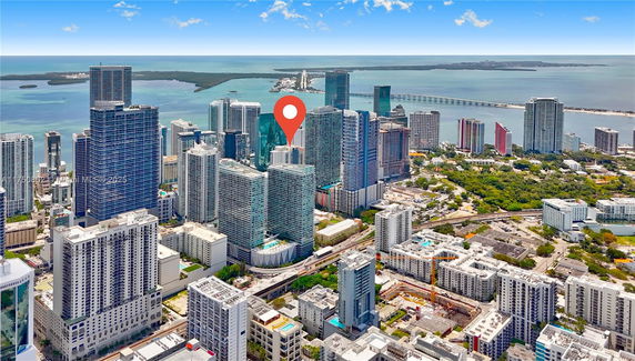 Aerial view of a cityscape with tall skyscrapers and a water body in the background.