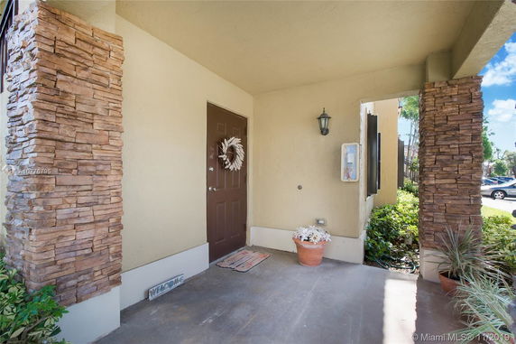 Front entrance of a house with brick columns and a brown door.