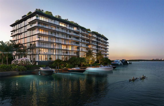 Front view of a modern, multi-story building with large glass windows and waterfront access.