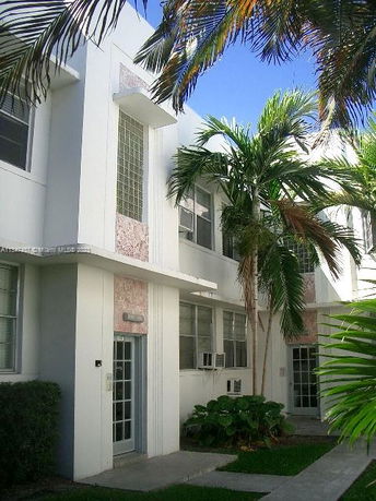 Front view of a multi-story building with large windows and palm trees nearby.