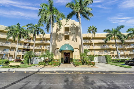 Front view of a multi-story residential building with palm trees.