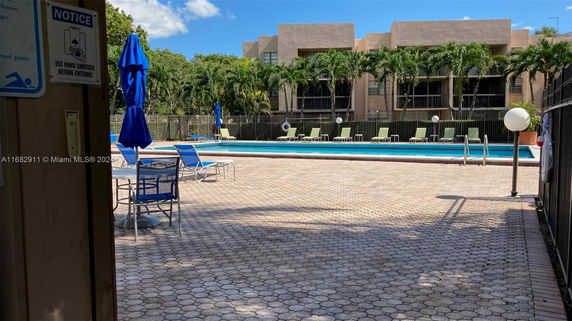 Outdoor swimming pool area with lounge chairs and umbrella setup.
