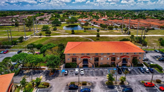Aerial view of residential buildings with a parking area and surrounding landscape.