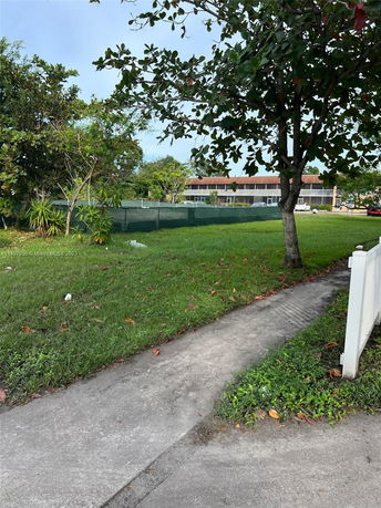View of a grassy area with trees and a walkway beside a building.