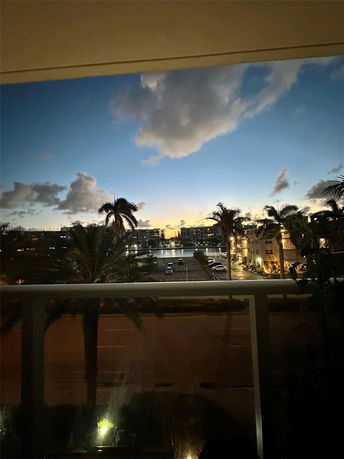 View from a balcony showing a broad horizon with a sunset sky above distant buildings.