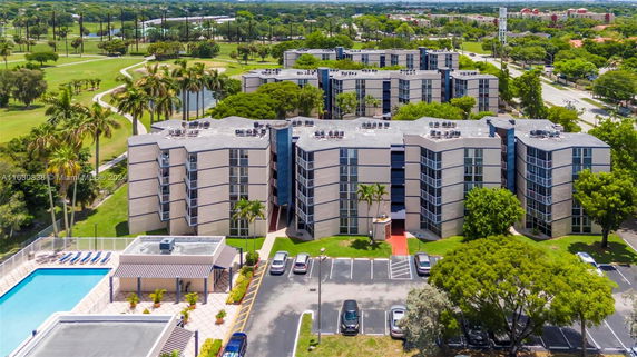 Aerial view of multiple modern buildings with surrounding green areas and a swimming pool.