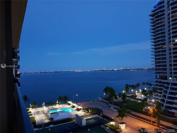 View of a city skyline across a body of water at dusk from a building.