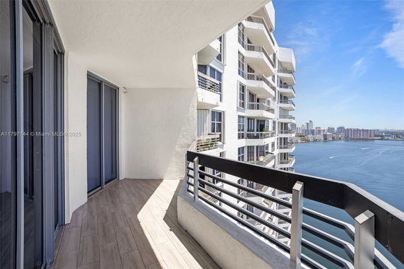 Balcony view from a high-rise building overlooking a body of water and city skyline.