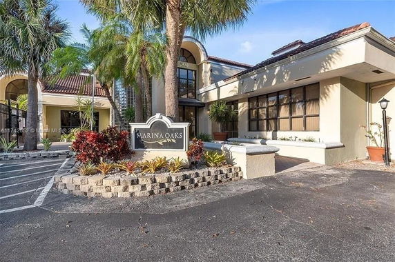 Front view of a building with a large entrance and tropical landscaping.