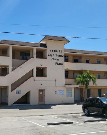 Front view of a three-story commercial building with labeled sign 'Lighthouse Point Plaza'.