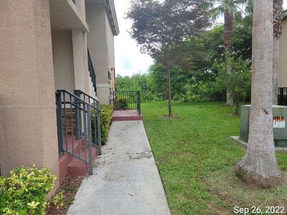Side view of a building with a walkway, lawn, and trees.