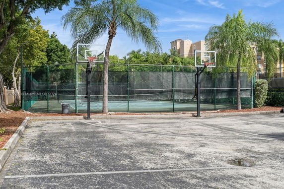 Outdoor basketball court with two hoops and surrounding fence.