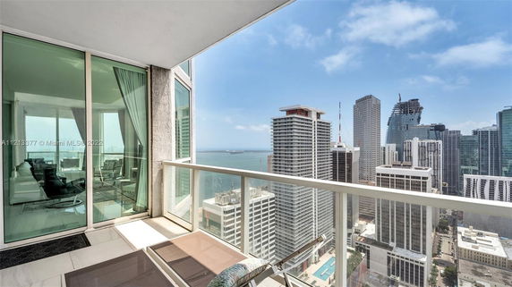 Panoramic view from a high-rise apartment balcony overlooking skyscrapers and the ocean.