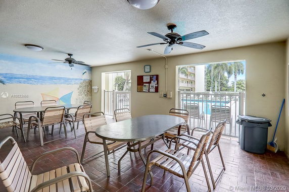 Indoor recreational area with tables, chairs, ceiling fans and a mural on the wall.
