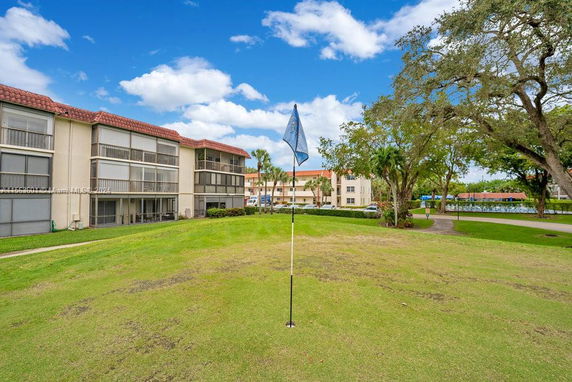 Back view of a multi-story residential building with screened balconies near a golf course.