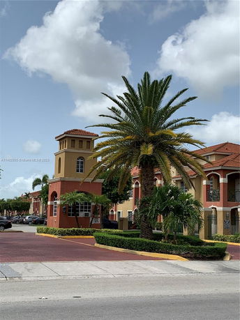 Front view of a multi-story building with a tower and red-tiled roofs.