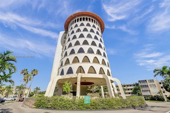 View of a tall, cylindrical building with arched windows and unique architectural design.