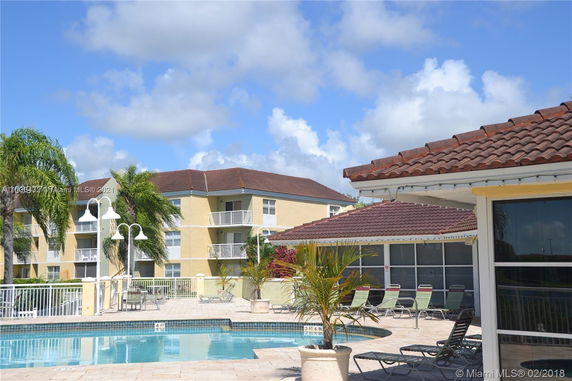 Outdoor swimming pool area with nearby buildings and lounge chairs.