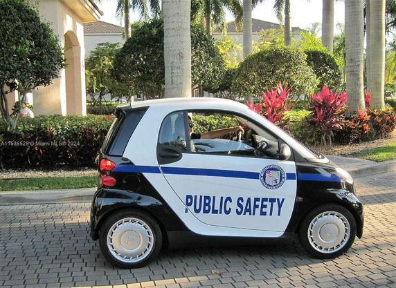 Small public safety vehicle parked on a paved driveway with surrounding greenery.
