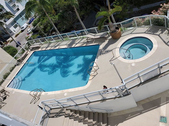Outdoor view of a swimming pool area with a hot tub on a building's deck.