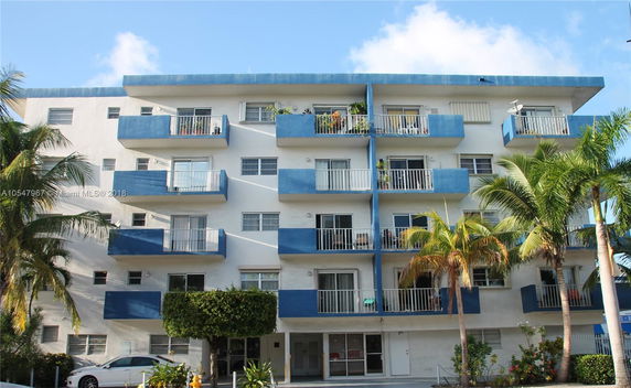 Front view of a multi-story apartment building with blue accents and balconies.