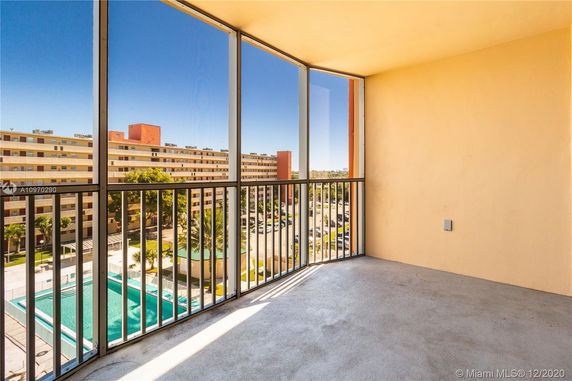 View from a balcony overlooking a pool and large residential building.
