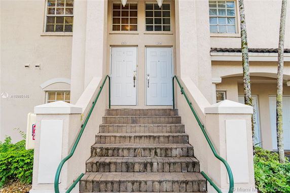 Front view of a building entrance with stairs leading to two white doors.
