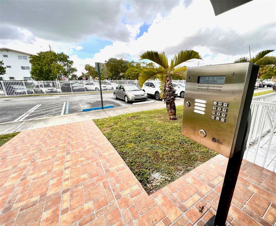 Outdoor parking area with a keypad entry system and several parked cars.