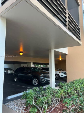 Covered parking area with multiple cars parked underneath a building.