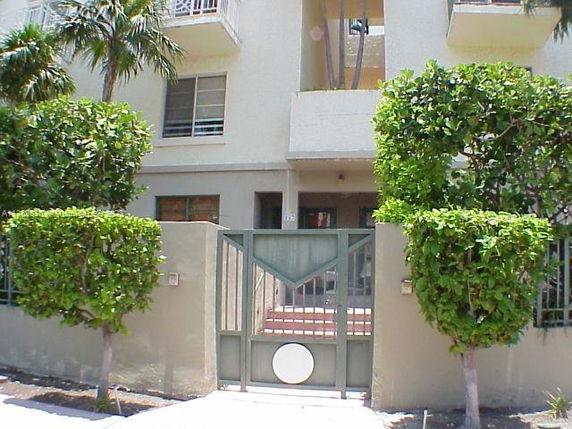 Front view of a multi-story building with a gated entrance and balconies.
