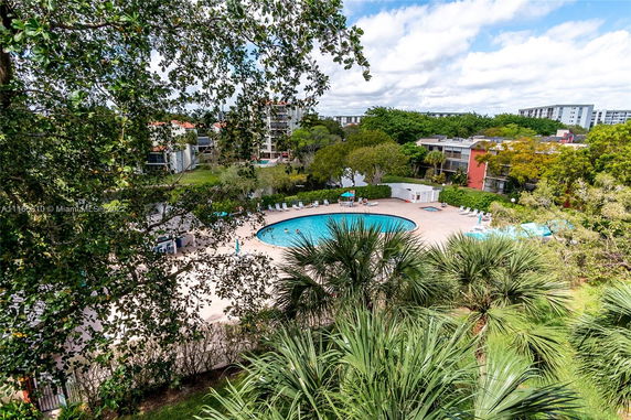View of a circular swimming pool surrounded by greenery and residential buildings.