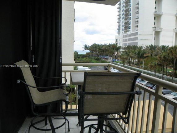 View from a balcony overlooking nearby high-rise buildings and palm trees.